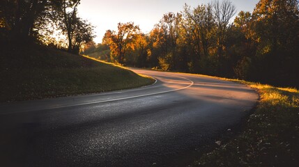Fototapeta premium Empty Winding Road Through Autumn Trees at Sunset.