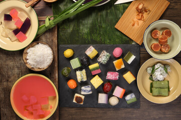 Traditional Malaysian desert Nonyah Kuih making preparing ingredients panadn leaf shredded coconut gula melaka  agar agar sagu spread over black slate messy rustic wood