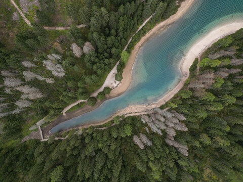 Aerial view of a scenic forest lake with turquoise water and sandy shore. Lago di Braies, Dolomites, Italy