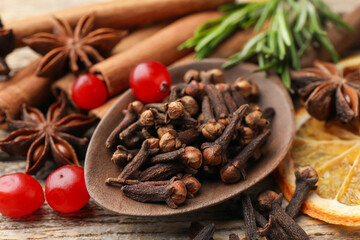 Different spices, cranberries, fresh rosemary and dry orange slice for mulled wine on wooden table, closeup