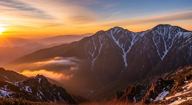 Golden hour bathes the snowcapped peaks of the majestic mountain range
