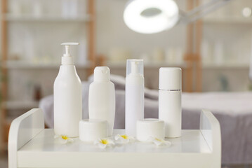 Beauty products in jars and bottles on white table in spa salon. Skin care cream and lotions for body treatments. Cosmetics on advertisement. Professional cosmetology and beauty concept