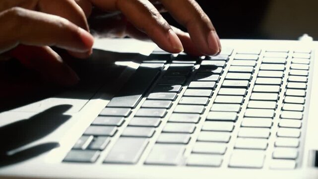 Fingers typing on a laptop keyboard. Focus selected.