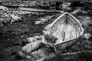An abandoned boat rests on the rocky shores of Peggy's Cove, capturing the rustic maritime charm of Nova Scotia's picturesque fishing village.