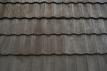 A detailed, high-angle close-up of dark grey, corrugated metal roof tiles, showing a repeating pattern of wavy curves and subtle texture. Perfect for 3d rendering.
