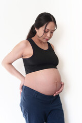 Profile view of young Asian pregnant woman holding while looking
