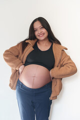 Beautiful young pregnant woman in good fit holds hands on her belly. Happy mother waiting for baby birth during pregnancy.