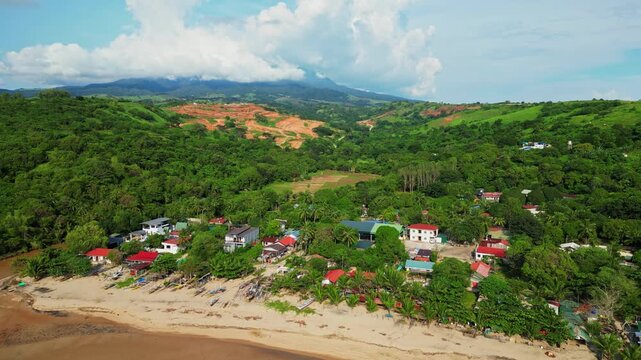 Upward aerial showing sandy shoreline of Quinawan Beach and brown waters as the drone rises past the coastline town, framed by lush hills and tropical scenery in Mariveles, Bataan.