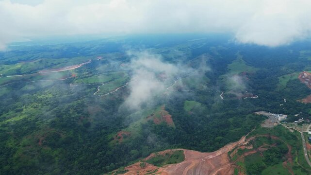 Sky‑high aerial of Quinawan Mountain View in Mariveles, Bataan, highlighting rolling green hills and coastline as drifting clouds pass through the frame, adding depth and motion.
