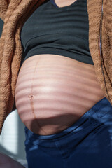 pregnancy, love, family and people concept - close up of pregnant woman making hand heart gesture on her belly