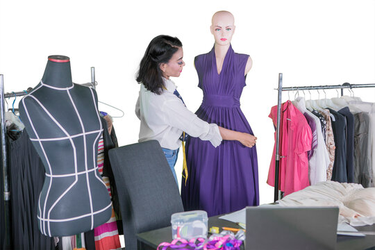 Asian female fashion designer working on a long purple dress with a white background - Powered by Adobe