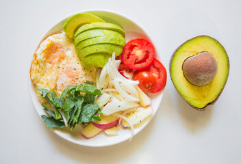 Healthy breakfast with fried egg, avocado and vegetables on white background