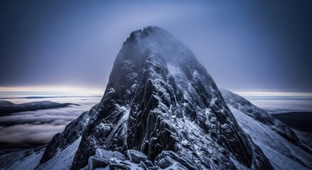 Majestic snow-capped mountain peak rising above a sea of clouds at twilight.