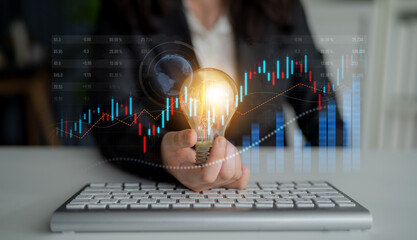 A business professional showcases a glowing light bulb representing innovative ideas against financial graphs, symbolizing growth and strategic planning in the workplace. Scalp