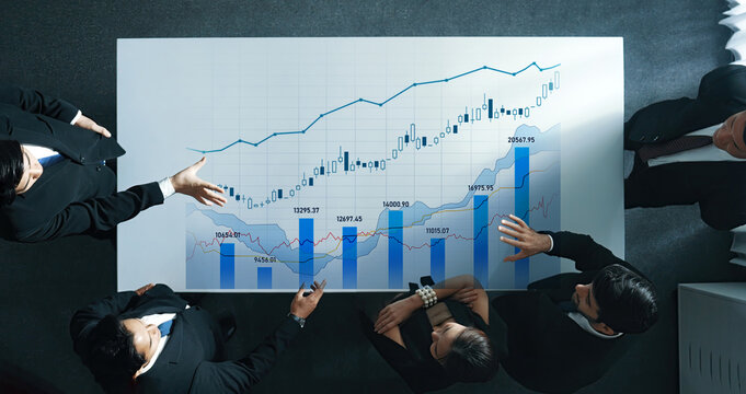 Business team gathered around a conference table reviewing financial data and charts, symbolizing teamwork and strategic planning for growth in a modern office. Scalp - Powered by Adobe