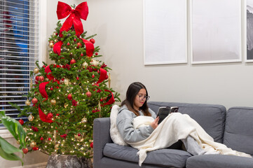 Teenager Reading on the Sofa With a Cozy Blanket. Teen Reading Comfortably Under a Blanket Indoors. christmas