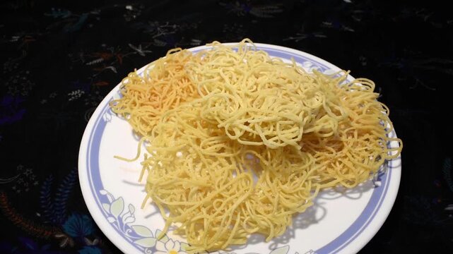 freshly fried noodles served on a plate, placed on a dinner table setting for soup or chopsuey