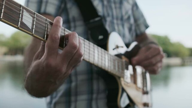 Musician hands playing electric guitar outdoors