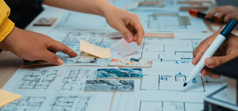 Hands engage in collaborative brainstorming over architectural plans and sketches, showcasing teamwork and creativity in a dynamic workspace filled with notes and drawings. SACTR