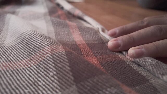 Close-up of a seamstress carefully pinning fabric to create a hem on a sewing machine. Detailed shot of hands working in a textile workshop, showcasing craftsmanship, precision, and the handmade garme