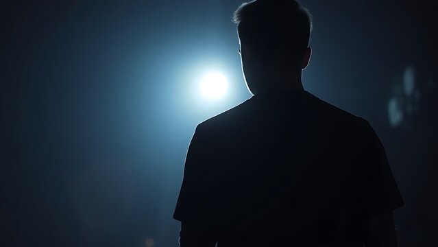 A silhouette in dim light with a faint glow, creating a mysterious and atmospheric mood.