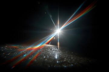 Bright lens flare creates rainbow beams on a dark background over a glittering surface