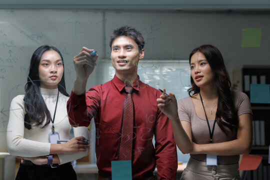 Business team collaborating on glass board presenting ideas