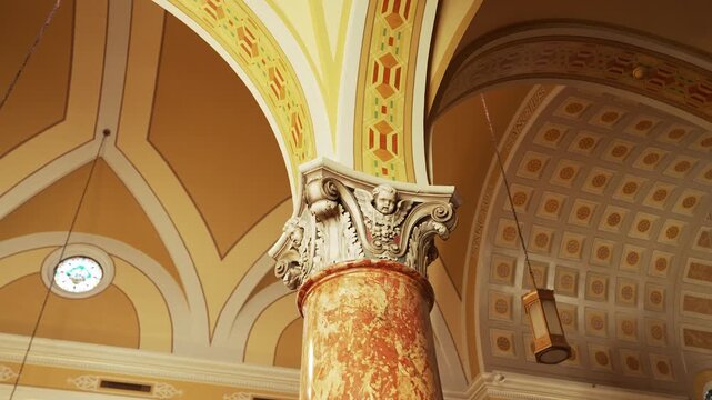Looking up at a baby angel statue in an old catholic church with stained glass windows and beautifuls designs. 