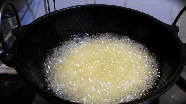deep frying boiled noodles in hot oil at gas stove.