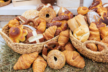 Baskets overflowing with different kinds of bread variety of shapes in local bakery setting.