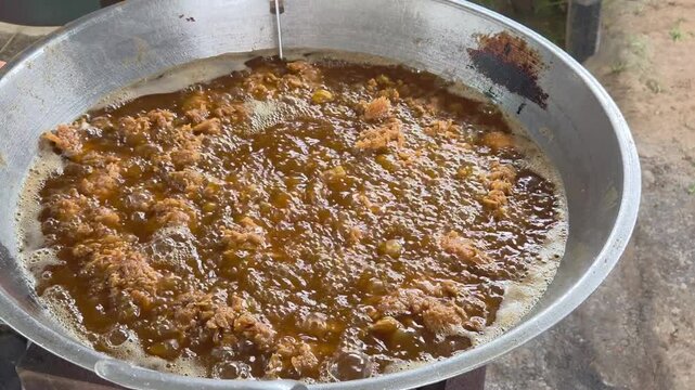 Crispy kentucky fried chicken being deep fried in vigorously boiling oil rich golden textures and floating crunchy crumbs