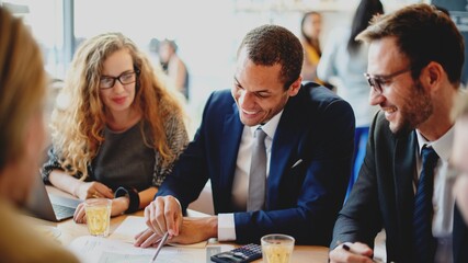 A diverse group of professionals, including a Black man in a suit collaborate in a meeting, discussing strategies and sharing ideas. Group of business community sharing ideas together