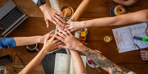 Diverse group of hands joining in teamwork over a wooden table. Collaborative teamwork with diverse hands. Teamwork and collaboration in a diverse setting.