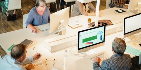 People working at computers in a modern office. Open workspace with diverse individuals collaborating. Office environment with teamwork and technology. Senior students in computer class.