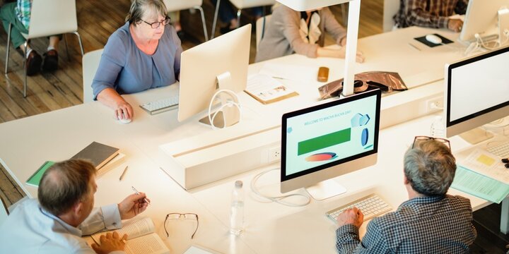 People working at computers in a modern office. Open workspace with diverse individuals collaborating. Office environment with teamwork and technology. Senior students in computer class.