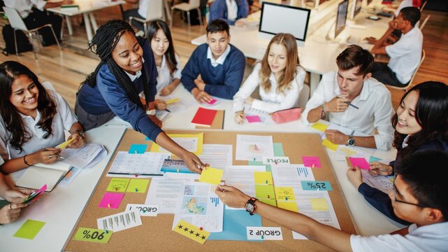 Diverse group of students collaborating around a table, sharing ideas and notes. Engaged in teamwork, brainstorming, and creative discussion in a classroom setting. Students working together in class. - Powered by Adobe