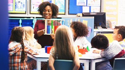 African American woman teacher in classroom with student. Black teacher teaching diverse group of students. Woman teacher with abacus teaching. Classroom learning, teacher, Diverse students learning