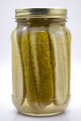 Close-up of a glass jar filled with whole dill pickles submerged in brine, sealed with a metal lid.