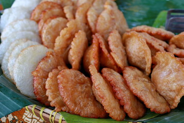 Kue Cucur, Assorted indonesian fried snacks arranged on banana leaf platter at outdoor market showcasing culinary traditions and local flavors.