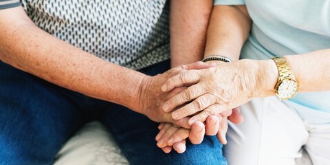 Close-up of elderly hands clasped together, symbolizing support and companionship. The image focuses on the warmth and connection between the individuals. Senior couple holding hands.