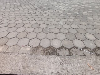 Repeating pattern of grey hexagonal concrete pavers.Close up view of interlocking geometric pavement.Outdoor flooring texture using modern grey hex blocks.