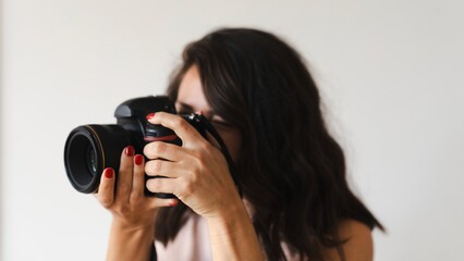 Content creator holding a camera, focusing on photography. Close-up of hands with red nails. Photography enthusiast capturing moments with a camera. Content creator taking photos with dslr camera.