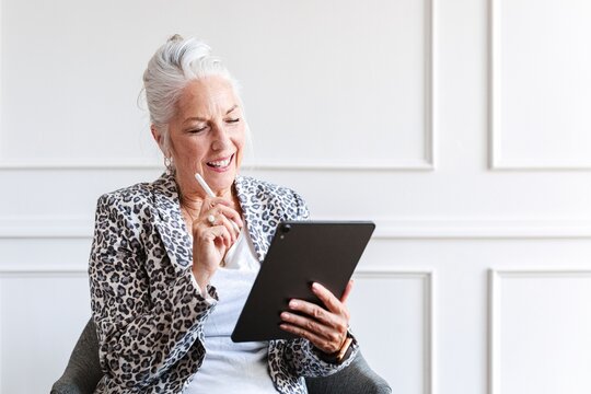 Senior Caucasian businesswoman using a tablet. smiling woman holding a tablet. Elderly woman with a tablet, female CEO leader working in office. Senior business businesswoman working on tablet