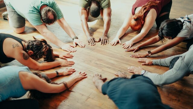 Group yoga class with diverse participants people stretching on wooden floor. Yoga poses, stretching, and diverse group of people in a calming yoga session. - Powered by Adobe