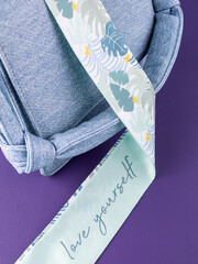 Close-up of a silk ribbon  with a tropical leaf pattern on a blue leather bag