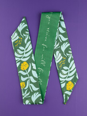 Close-up of a silk ribbon with a tropical leaf pattern  on purple background