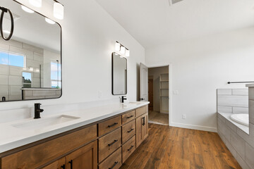 A spacious bathroom featuring two sinks, two mirrors, and a bathtub