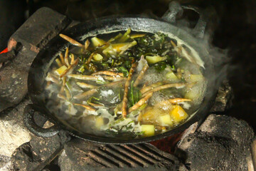 traditional cooking on an old stove. cooking vegetable soup in a black pan