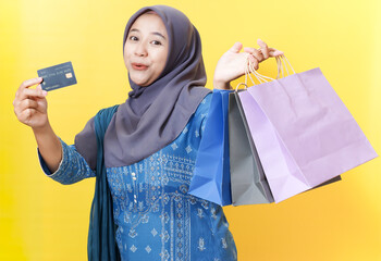 Woman in hijab with shopping bags and credit card.
