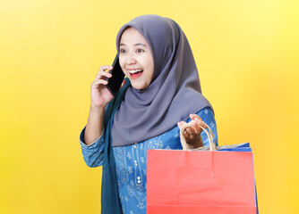 Woman in hijab talking on phone with shopping bags.